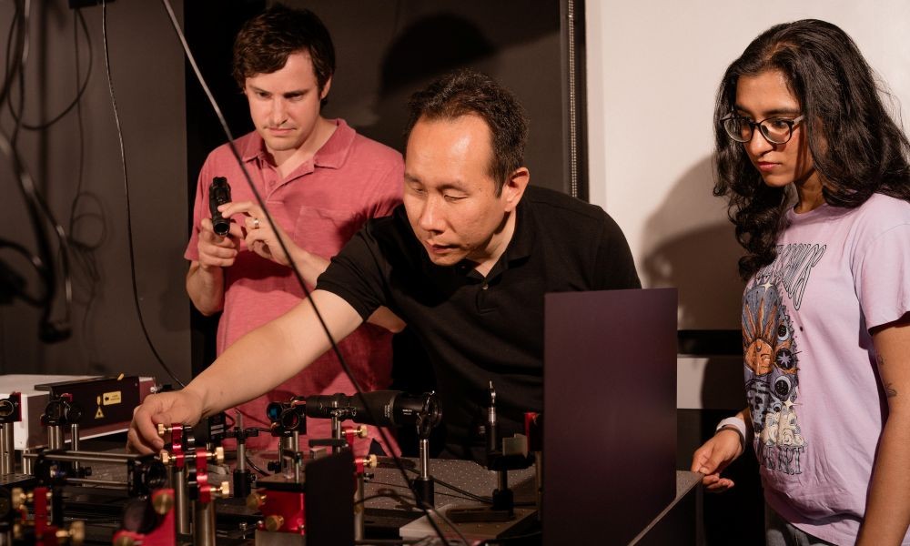 Boston University College of Engineering Associate Professor Jerry Chen, center, with senior scientist Andrew Blaeser to the left, and former undergraduate research assistant Rhea Singh to the right, working with a Quadroscope, a custom, two-photon mesoscope. Credit: Christopher McIntosh.