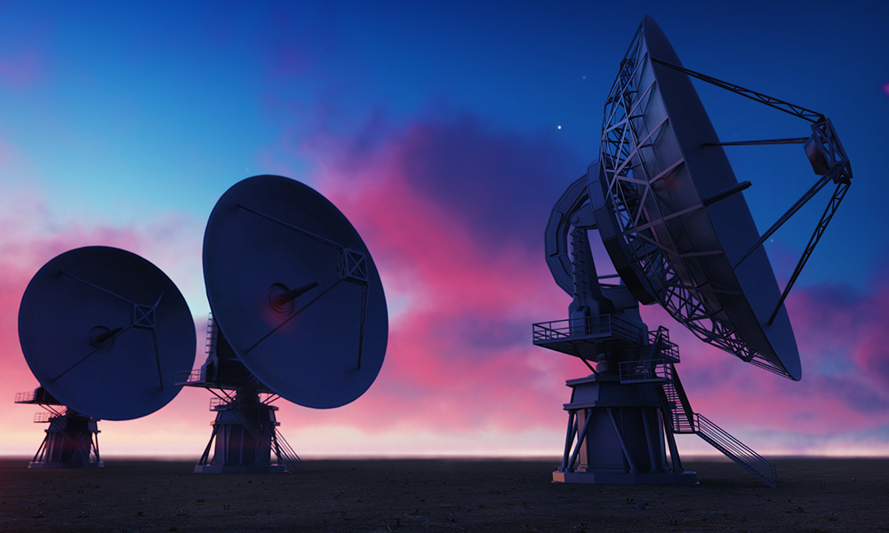 Ground-based telescopes silhouetted against pink and blue sky