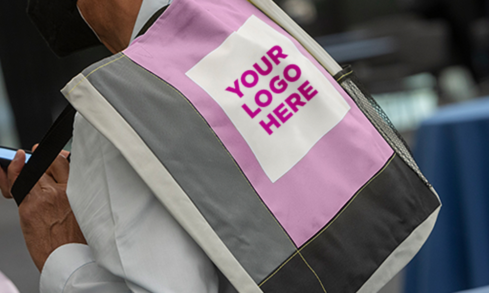 A person has a purple bag over their shoulder with the words "your logo here" written in purple text.