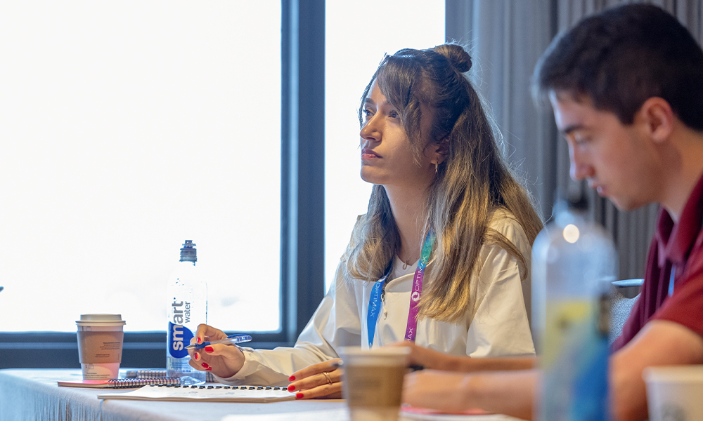 Two attendees sitting at a table, listening to a course instruction. 