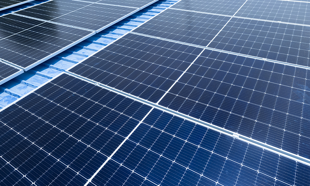 Rows of dark blue solar panels installed on a rooftop for photovoltaic energy generation.