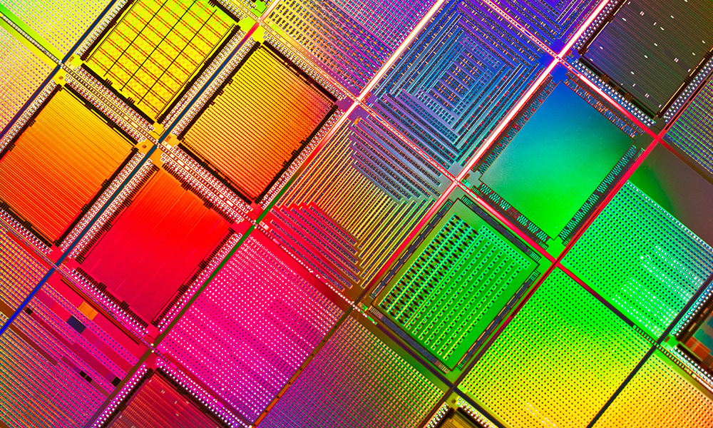 Colorful semiconductor wafer with intricate patterns and grids in rainbow hues.