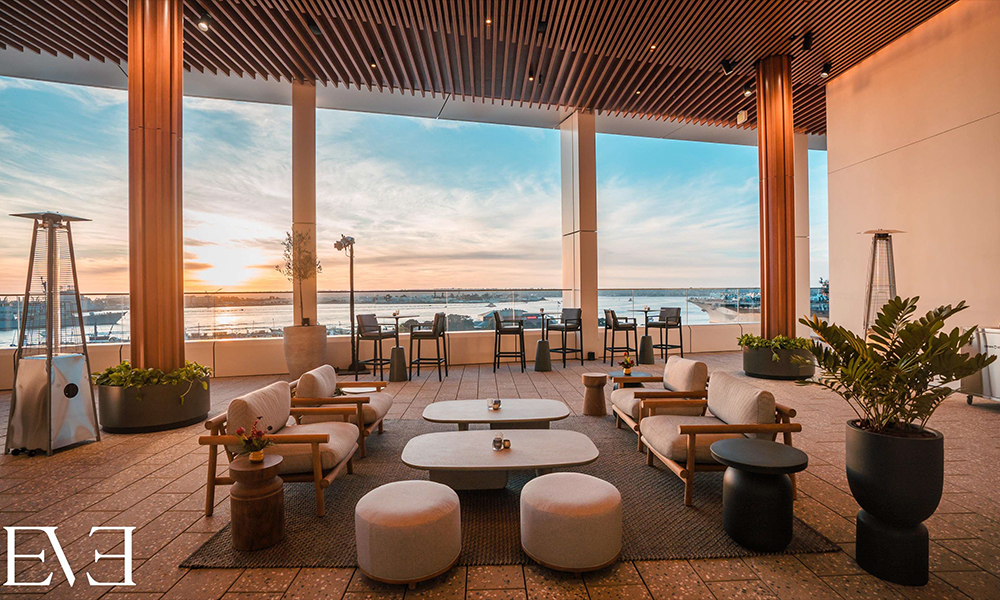 The EVE event space, with large windows overlooking the water and mid-century furniture and seating.  