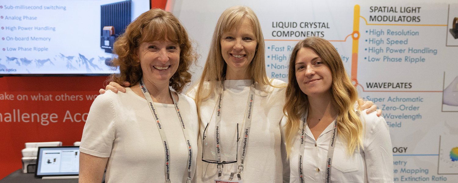 Three female exhibition attendees stand together