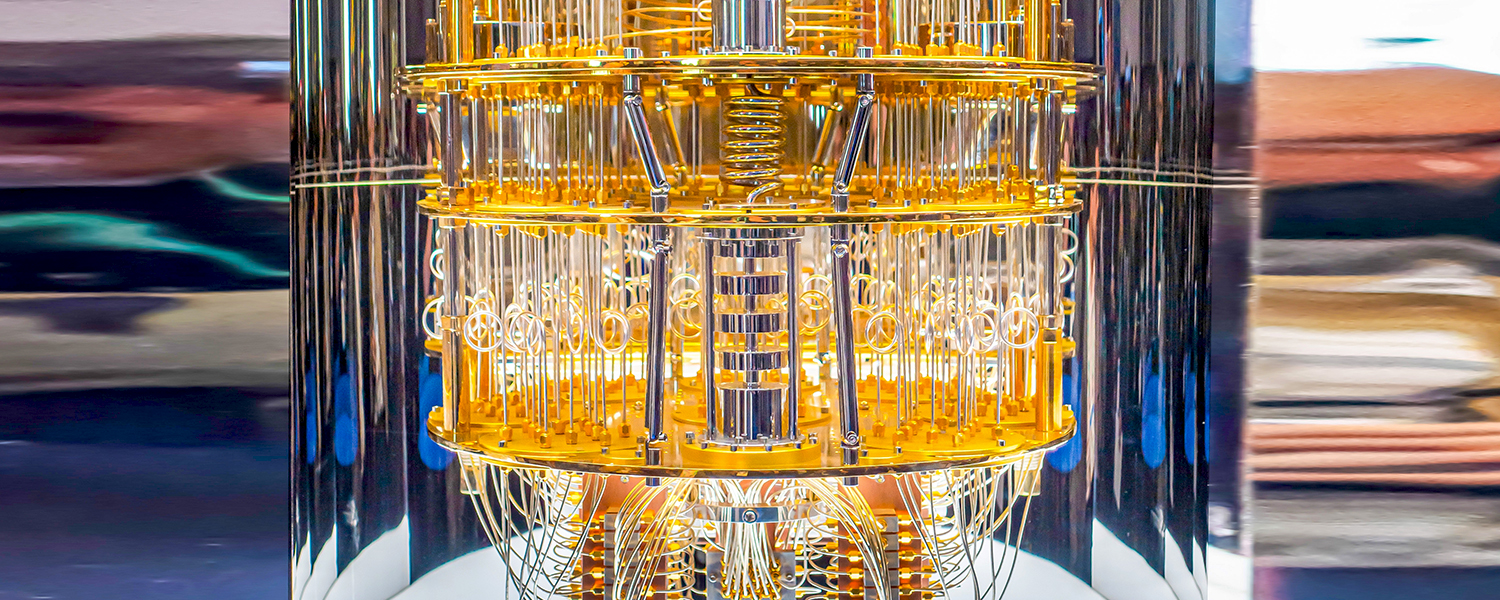 A quantum computer’s intricate inner workings are showcased, featuring a multi-layered structure with gold-colored components, including wires, coils, and other precisely arranged elements. The complex design is highlighted against a blurred background, emphasizing the advanced engineering behind quantum computing.