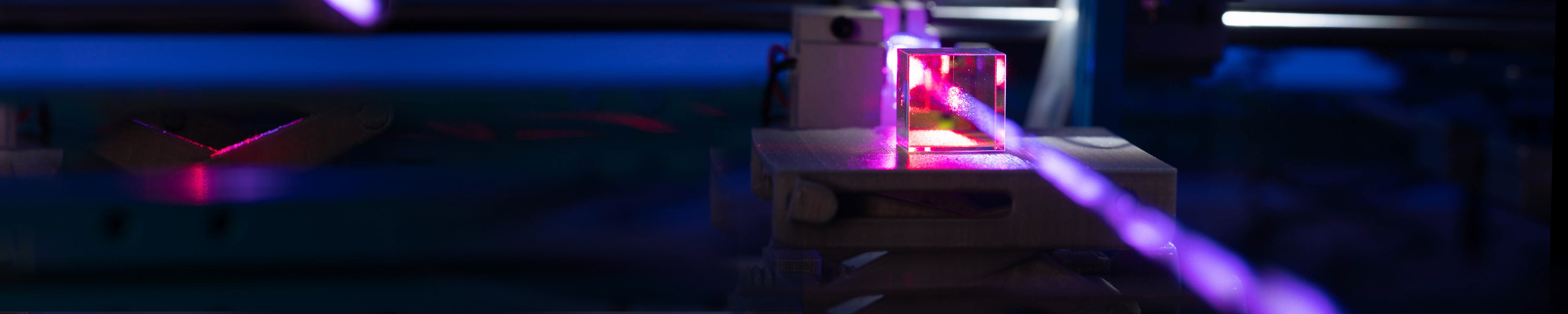 A purple laser shoots towards the viewer through a square glass lens