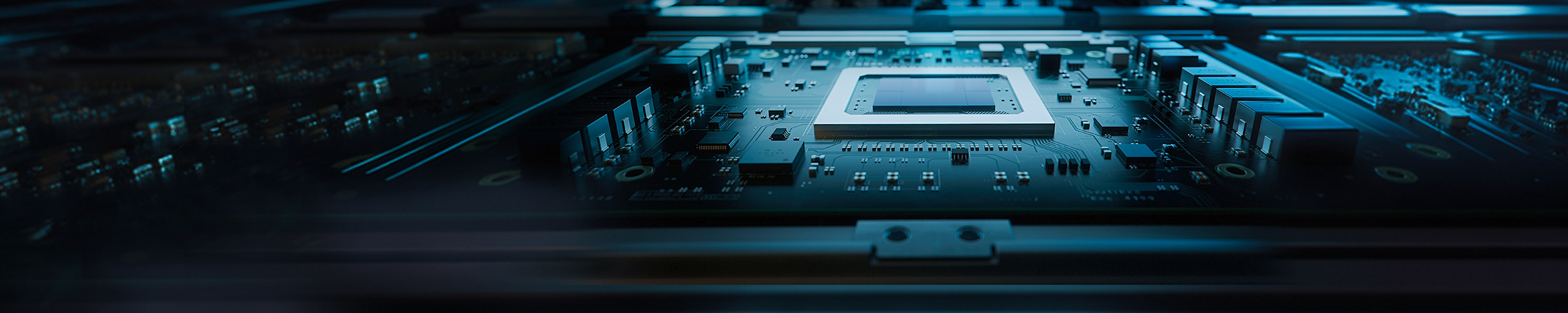 Close-up view of an electronic circuit board inside a computing system, featuring a rectangular central processor or chip socket mounted on a dark teal motherboard. Surrounding the chip are fine traces, capacitors, and integrated components arranged in precise rows.