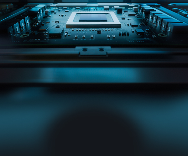 Close-up view of an electronic circuit board inside a computing system, featuring a rectangular central processor or chip socket mounted on a dark teal motherboard. Surrounding the chip are fine traces, capacitors, and integrated components arranged in precise rows.