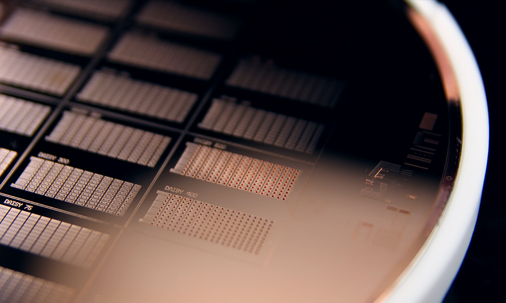 Close-up of a circular silicon wafer featuring a grid of integrated circuits. Each chip displays intricate patterns and structures, showcasing the complexity of semiconductor microfabrication. 