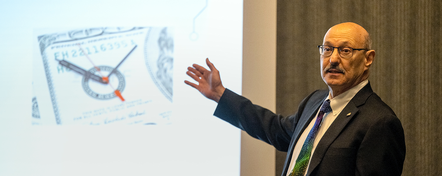 Harry Levinson gestures toward a presentation screen, while teaching a course.
