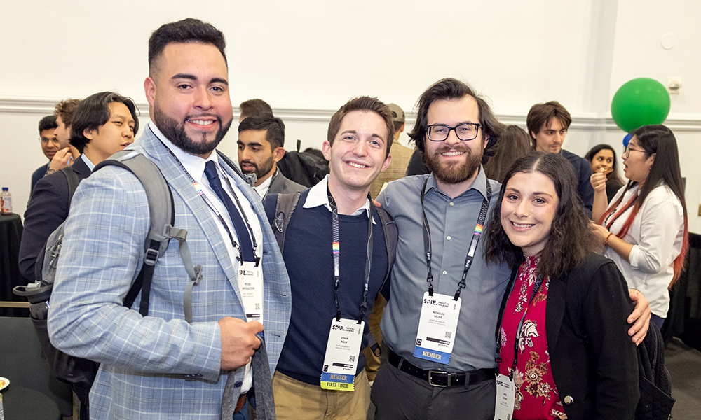 Four attendees at a conference stand together and pose, smiling for the camera