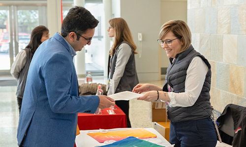 Attendees engage in one-on-one conversations and exchange materials at the SPIE Job Fair, surrounded by tables and participants in a busy networking environment.