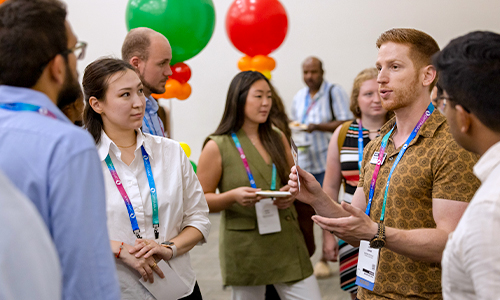 Participants engage in conversation during an SPIE Career Speed Mentoring event, with colorful balloons and name tags visible in a lively indoor setting.