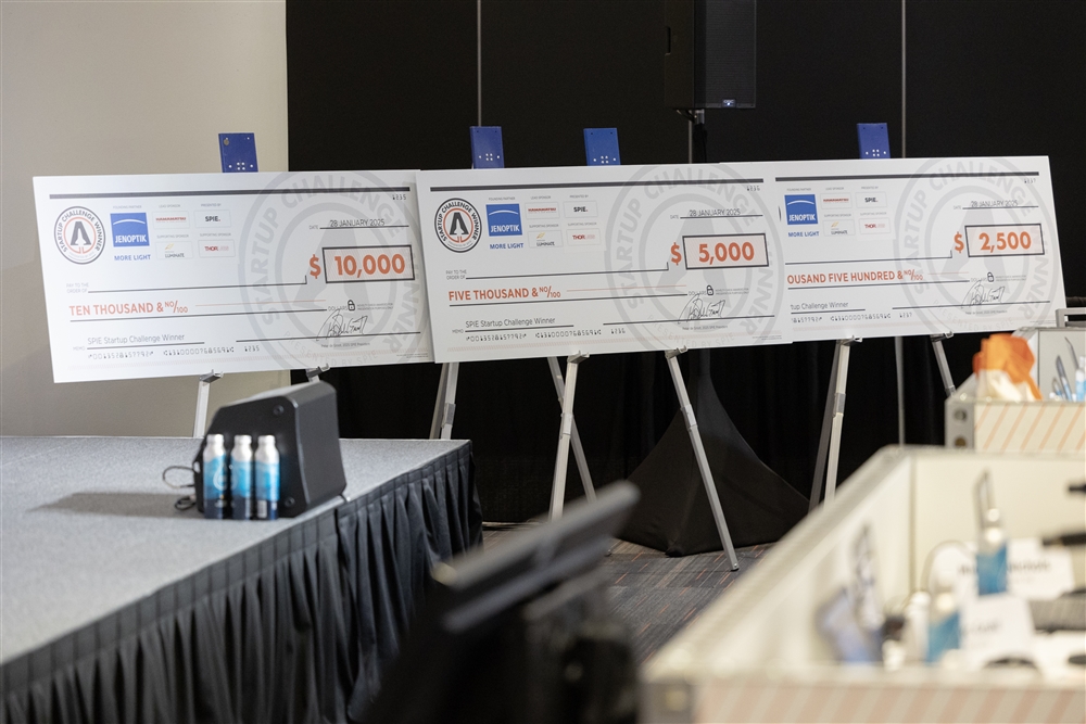 Three ceremonial checks from the 2025 Startup Challenge are displayed on stands. Sponsored by Endgame, Inc., the checks represent awards for the competition: $10,000 for the winner, $5,000 for the runner-up, and $2,500 for third place.