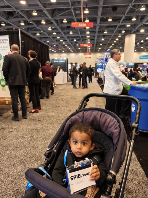 Roopa Prakash's child enjoys the Photonics West exhibition hall, proudly displaying his SPIE Youth Badge.