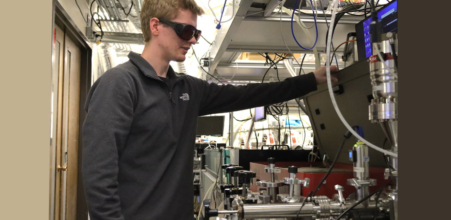 2025 recipient of the Nick Cobb Memorial Scholarship Clay Klein, in his lab at JILA, opening the part of the system that upconverts pulsed light from an infrared laser into extreme ultraviolet light through a process known as high harmonic generation. 